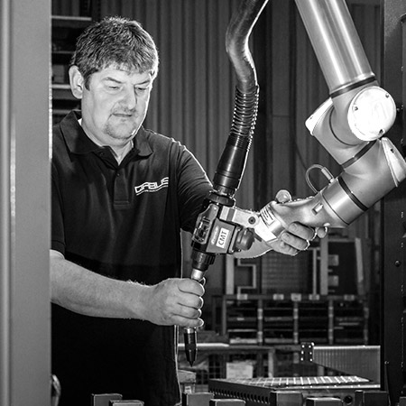 Mitarbeiter an einer Roboter-Schweißstation