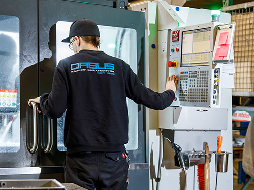 Mitarbeiter an einer CNC Fräse bei QABUS