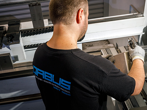 Mitarbeitender von QABUS bei der Qualitätskontrolle abgekanteter Bleche